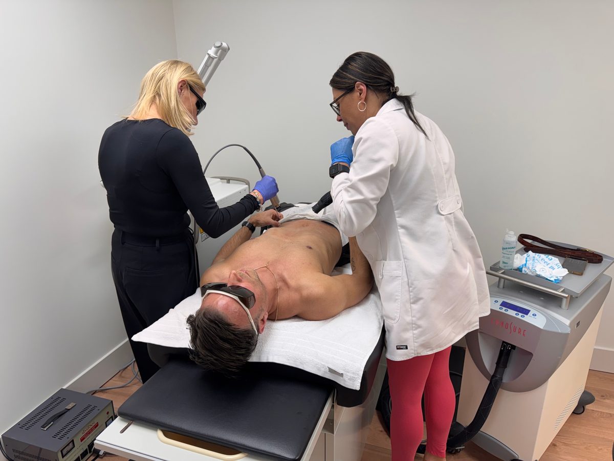 Two TRU Integrative Wellness providers performing laser cherry angioma removal on a male patient