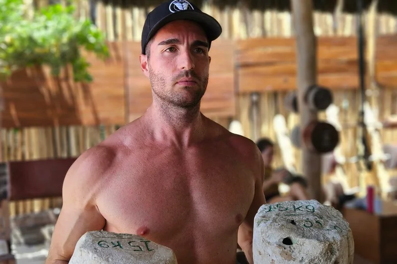 Mauro holding stone weights outdoors, representing men's vitality and confidence at TRU Integrative Wellness